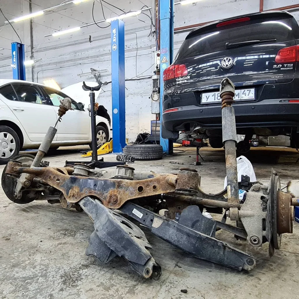 Задняя подвеска VW Tiguan в сборе с подрамником на полу ремзоны, на фоне сам автомобиль